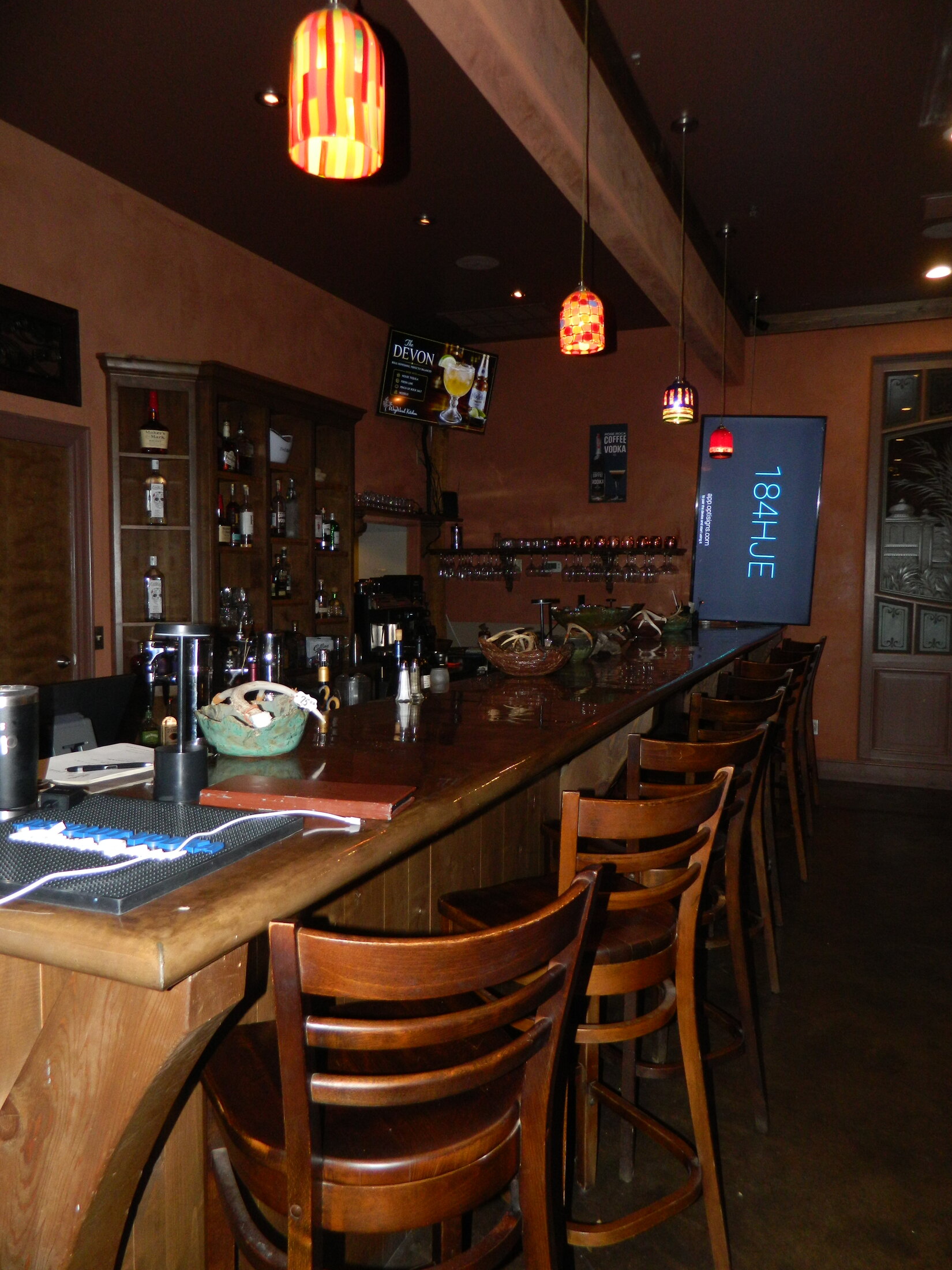 The warm wood bar and colorful pendant lights inside The WayWard Kitchen